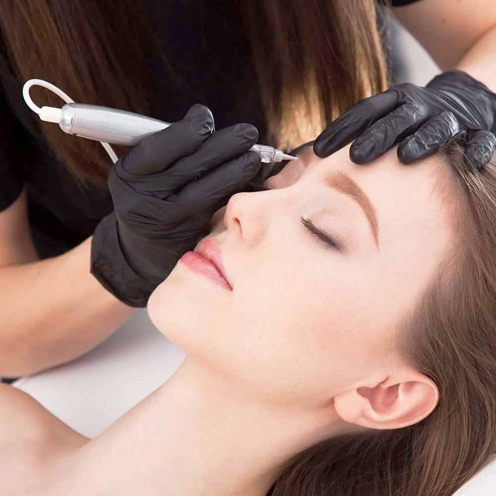 Woman receiving cosmetic tattooing for eyebrow enhancement at a clinic.