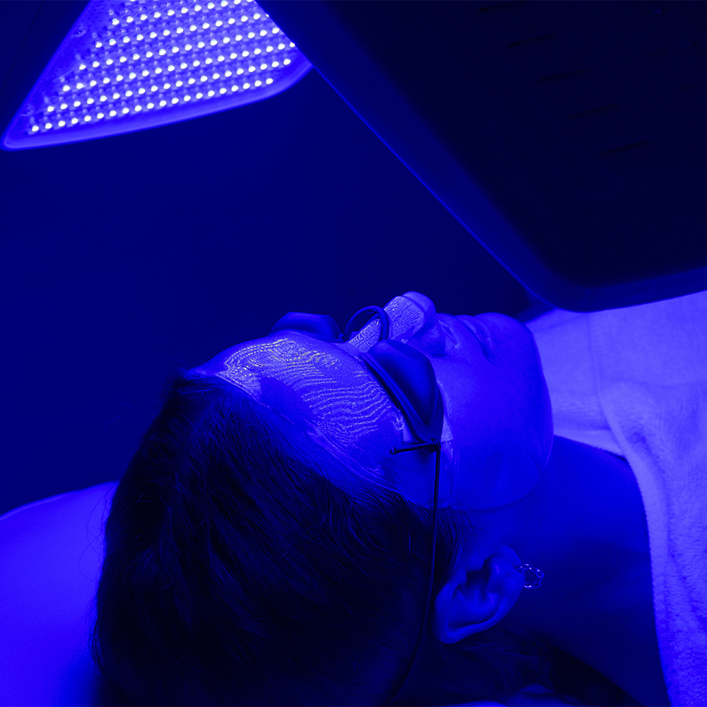 Female patient receiving blue LED light therapy for skin rejuvenation at Janine's Skin & Laser Clinic.